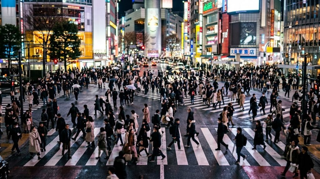 crowds crossing the illuminated Shibuya Scramble crossing in Tokyo at night