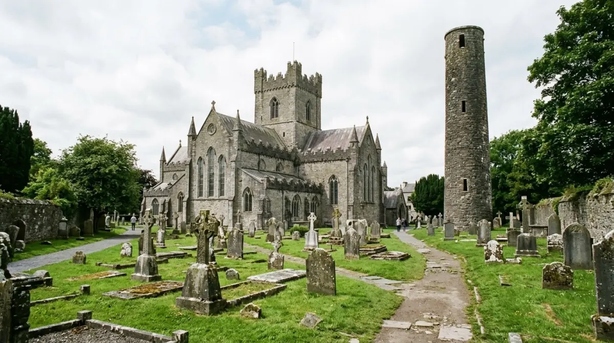 A medieval stone cathedral with a tall round tower beside it and an old graveyard, St Canice's Cathedral, Kilkenny, Ireland