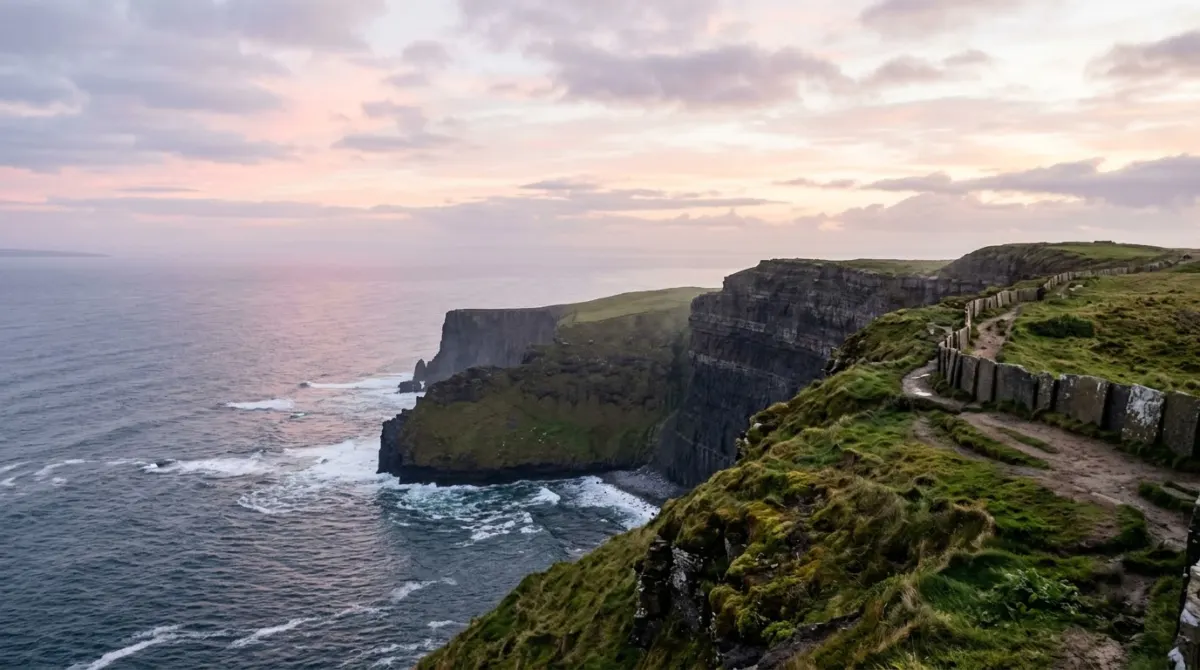 Tall dark sea cliffs dropping into the Atlantic at dawn with soft pink light and no people, Cliffs of Moher, County Clare, Ireland