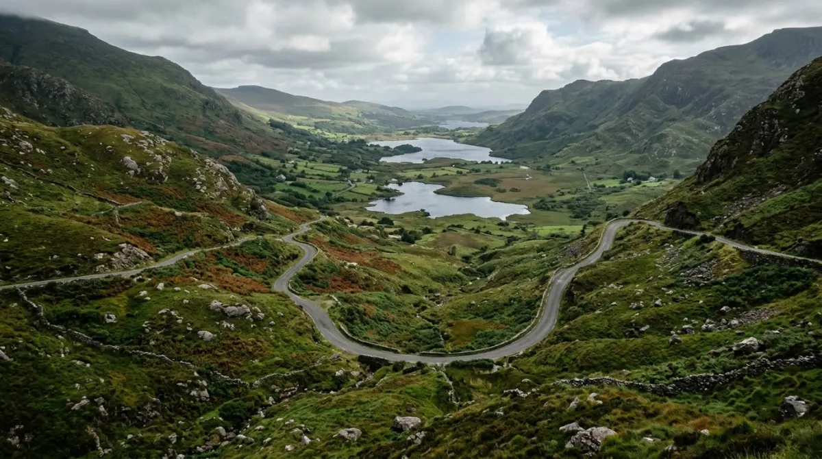A winding road through a green mountain pass with lakes below, County Kerry, Ireland