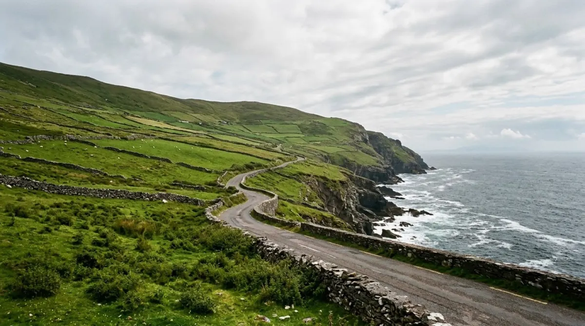 A coastal road winding above the Atlantic with green fields and stone walls, west of Ireland