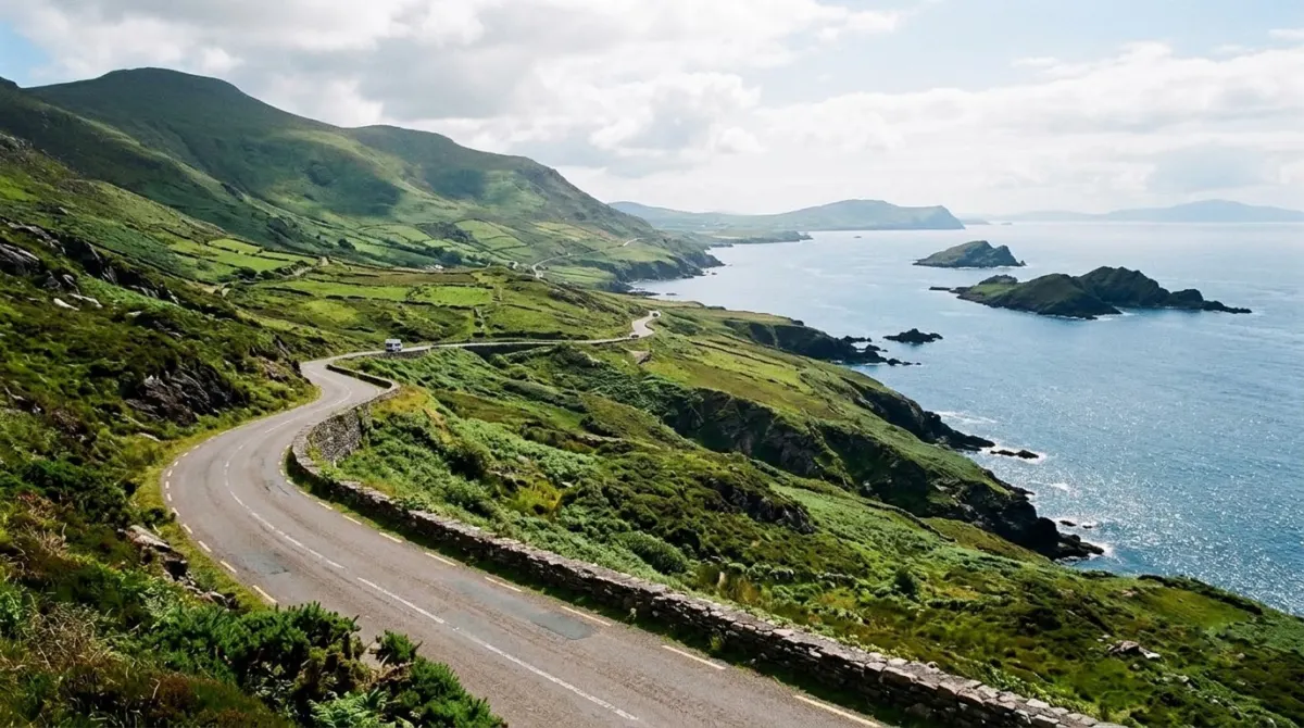 A coastal road high above a blue bay with islands offshore and green hills, Ring of Kerry, Ireland