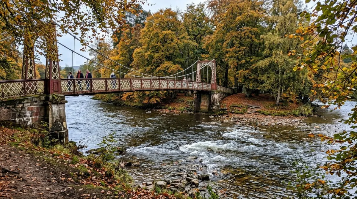 A Victorian iron footbridge crossing to wooded islands in a fast clear river in autumn, Ness Islands, Inverness, Scotland
