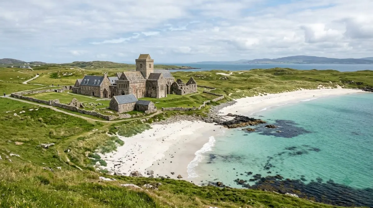 Old stone monastery buildings beside white sand and clear turquoise water on a quiet island, Iona, Scotland