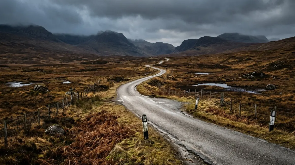 An empty single-track road crossing brown moorland under low winter light and dark clouds, Skye, Scotland