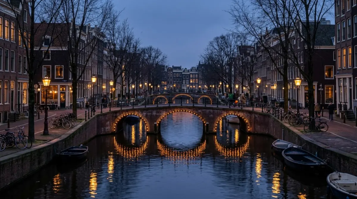 Arched canal bridges strung with lights reflected in dark water at dusk in winter, Amsterdam, Netherlands