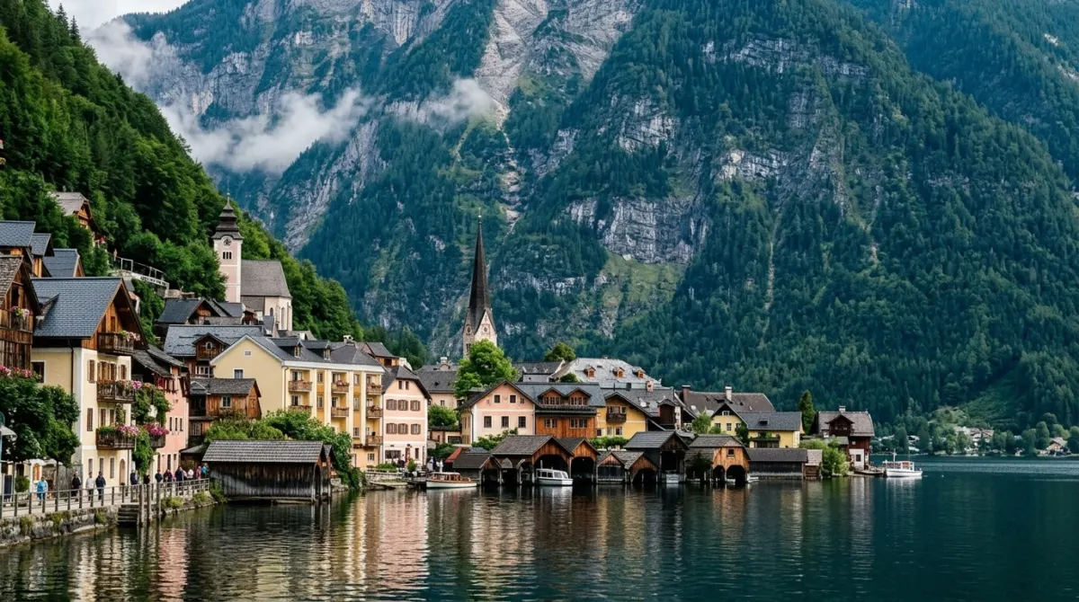 A lakeside village of pastel houses and a church spire below steep forested mountains, Hallstatt, Austria