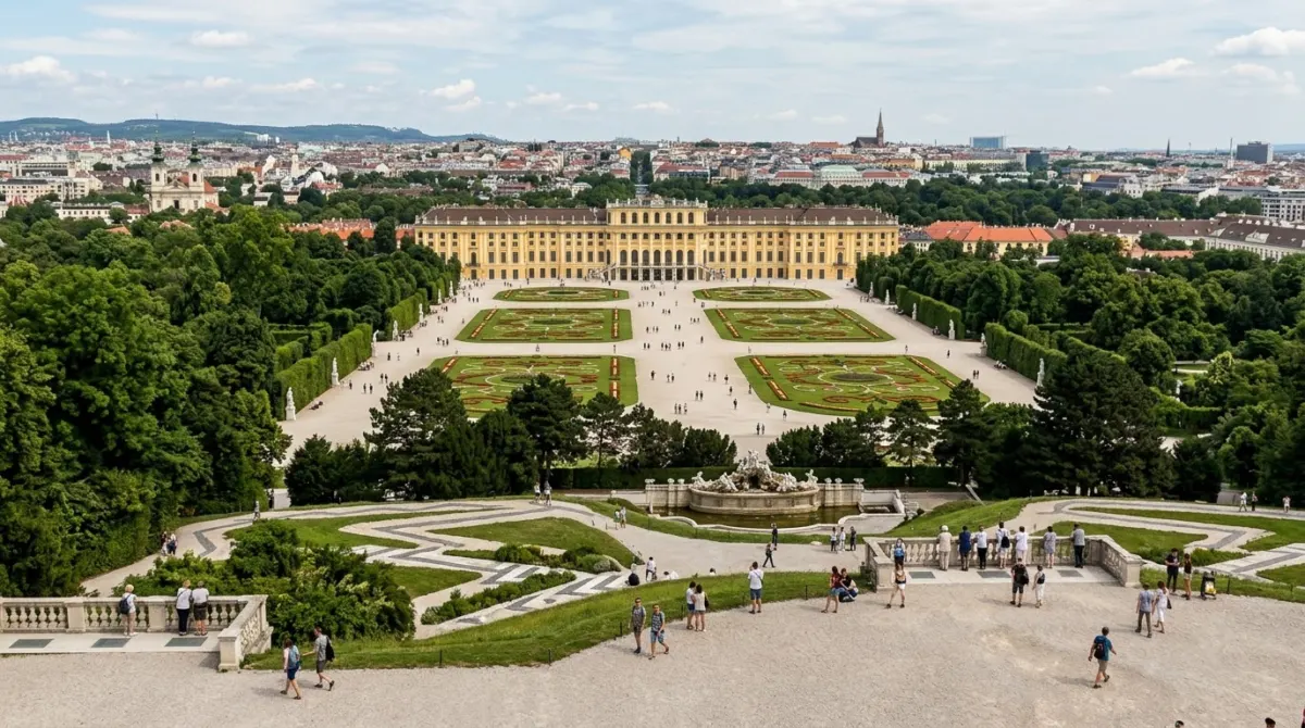 View from the Gloriette hill down over formal parterre gardens and fountains to the yellow palace and city beyond, Schönbrunn, Vienna, Austria