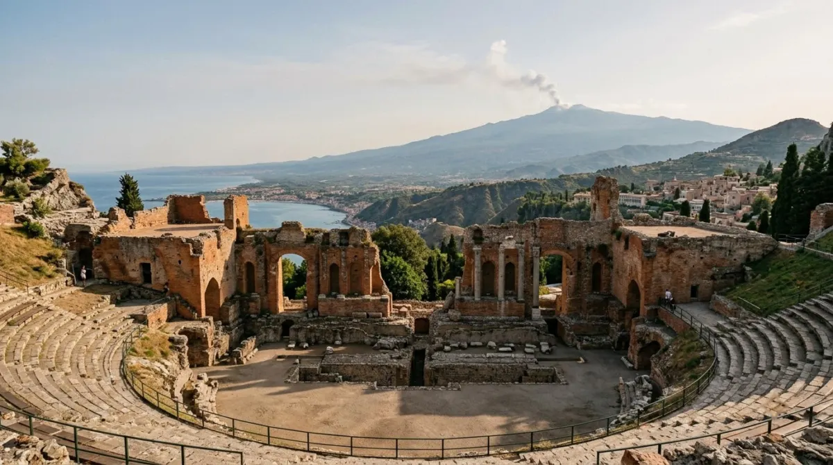 Ancient stone theatre ruins on a hillside with a smoking volcano framed behind the stage, Greek theatre, Taormina, Italy