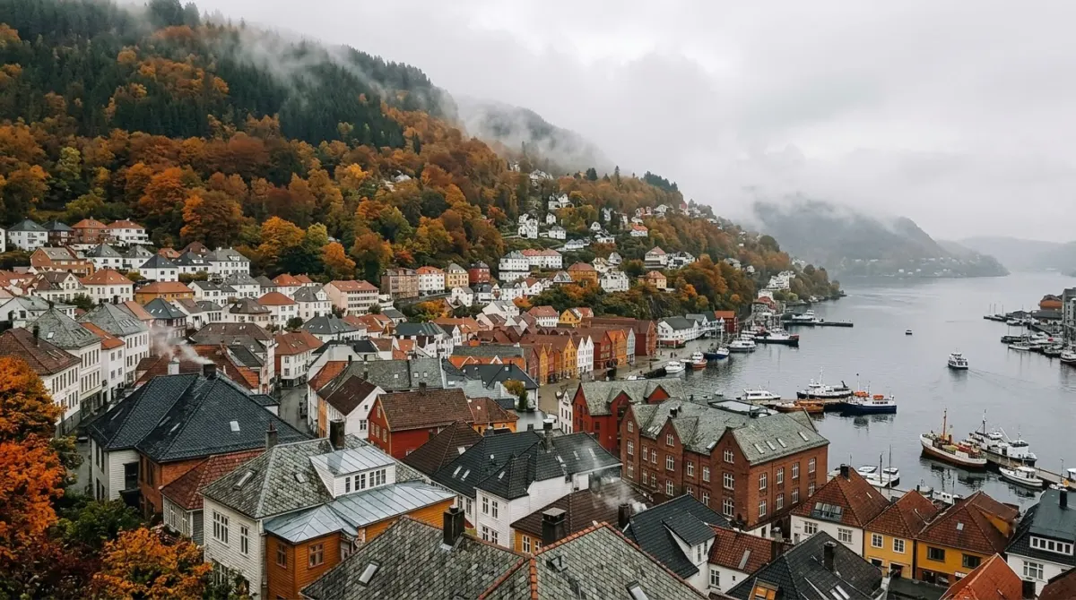 Hillsides of orange and yellow autumn trees rising above wet rooftops and a misty harbour, Bergen, Norway
