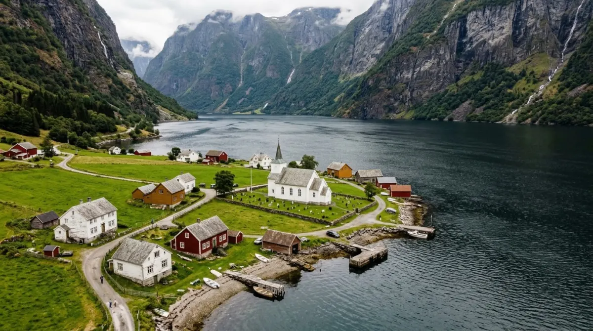 A white wooden church and scattered houses on a narrow green shore of a vast fjord, Sognefjord, Norway