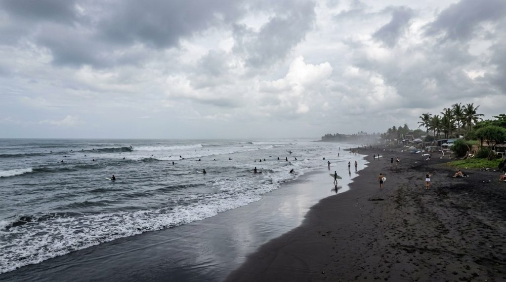 The dark volcanic sand beach at Canggu, Bali with surfers
