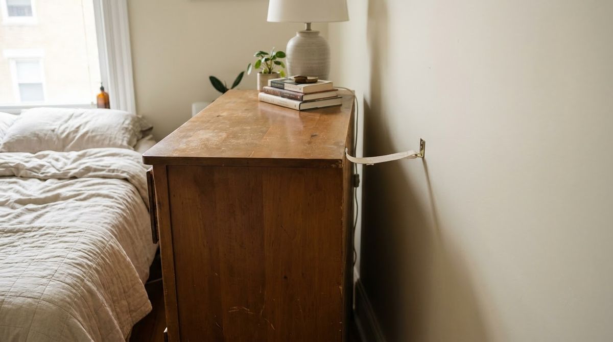 Anti-tip strap connecting the back of a bedroom dresser to the wall Anti-tip strap connecting the back of a bedroom dresser to the wall
