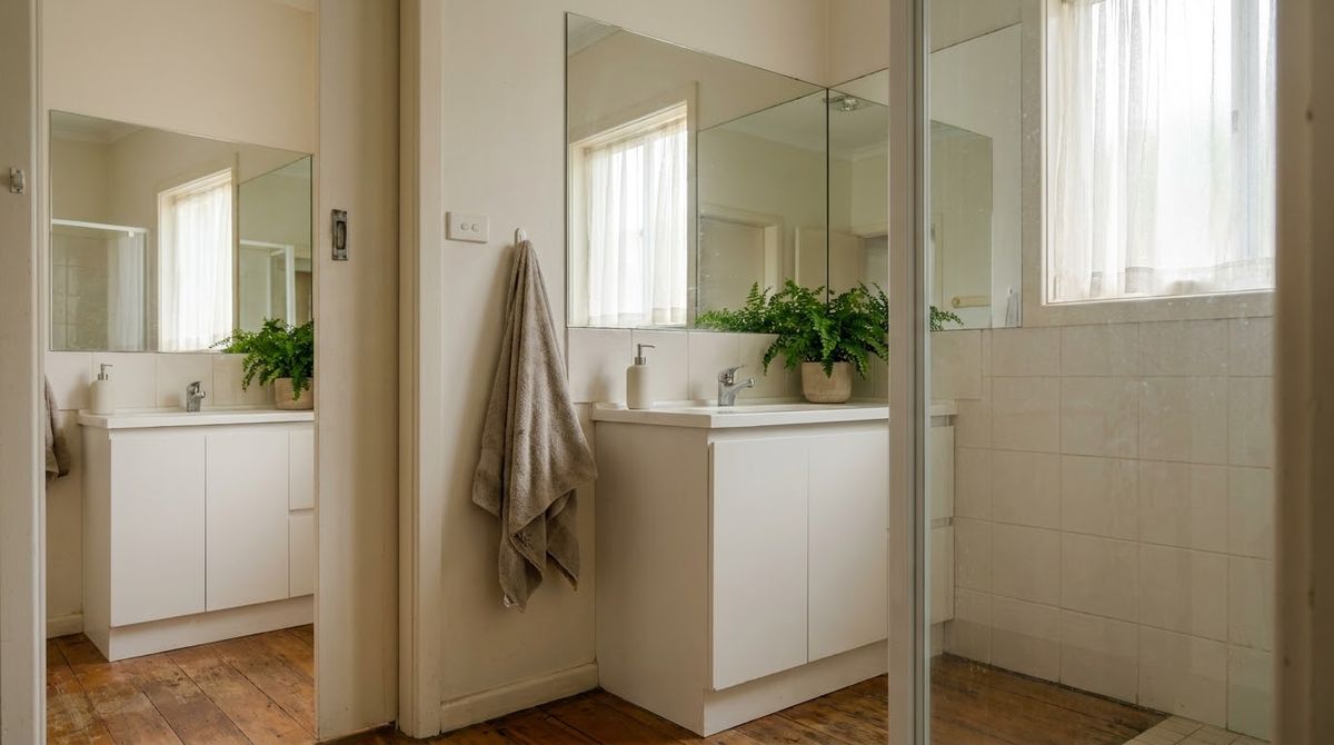Large mirror above a small bathroom vanity reflecting window light